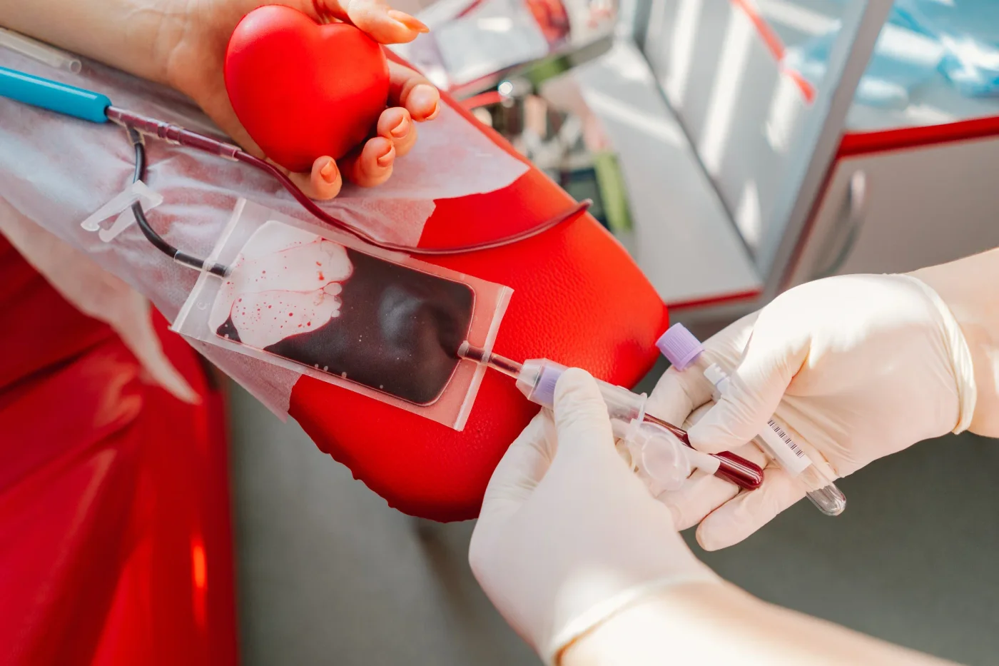 Persona donando sangre mientras sostiene una pelota con forma de corazón